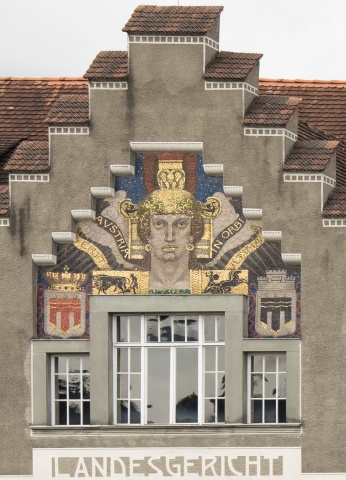 Austria-Kopf am Landesgericht Feldkirch mit den Wappen von Vorarlberg (mit rudolphinischer Hauskrone) und Feldkirch (mit Mauerkrone) sowie den Emblemen von Krieg (Streitwagen) und Frieden (Ochsengespann) und der Inschrift: „Austria erit in orbi ultima“. © Erhard Sprenger/Feldkirch